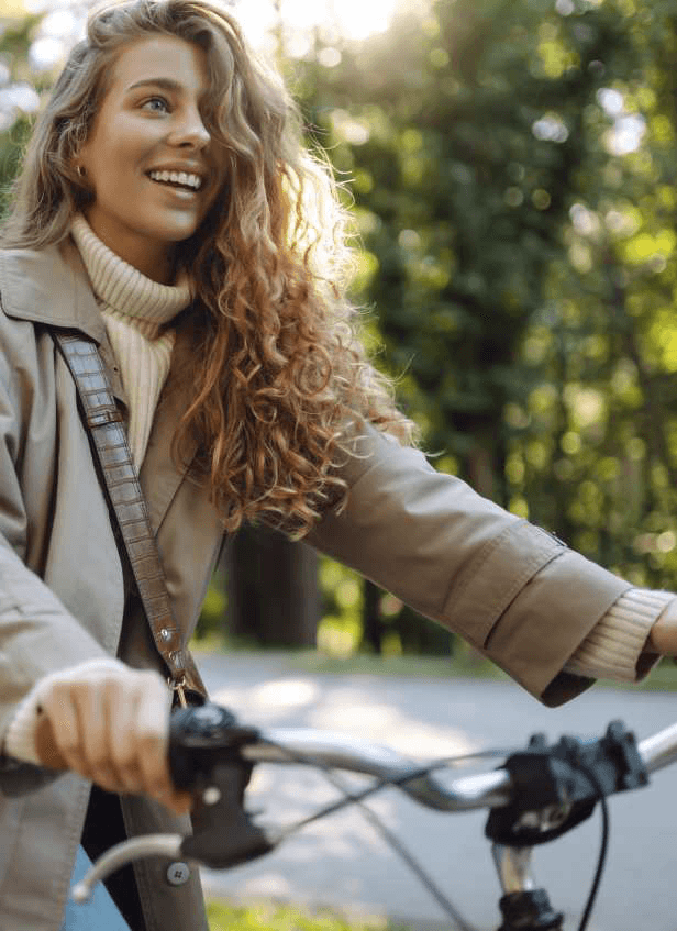 A woman riding a bicycle along an autumn path in warm afternoon light